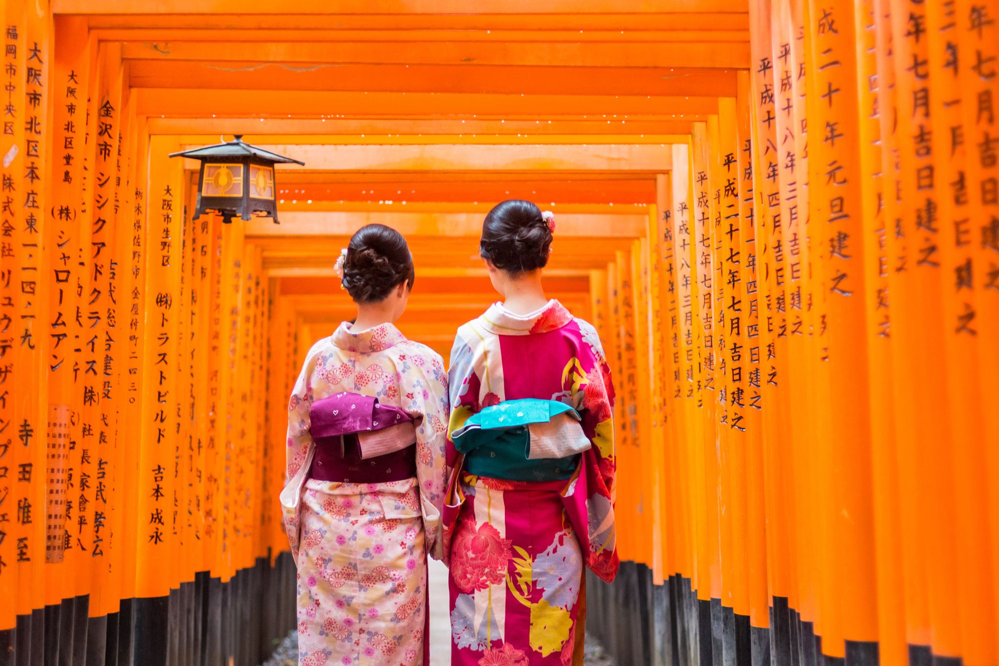 Due donne in kimono nel tunnel di torii vermigli (Senbon Torii) del Santuario Fushimi Inari Taisha, Kyoto, Giappone